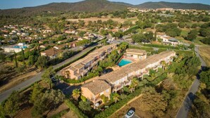 An aerial view of a residential area with houses, a swimming pool, and a hilly landscape in the background. - Entre mer & campagne | Maison T3 + accès piscine (Roquebrune sur Argens)