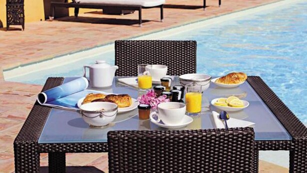 A poolside breakfast setup with lounge chairs, a table with breakfast items, and a pool in the background. - Séjour inoubliable en Provence | Maison + jardin (Roquebrune sur Argens)