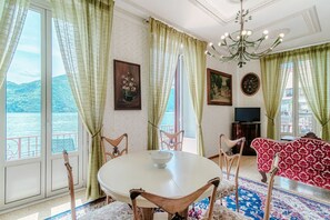 Een kamer met een eettafel, stoelen, een kroonluchter en een bank.