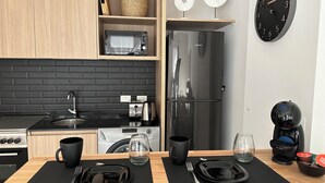 Una cocina moderna con protector contra salpicaduras de ladrillo negro, armarios de madera, un refrigerador de acero inoxidable y un reloj montado en la pared.