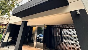 Un edificio moderno de varios pisos, con amplios ventanales y un acceso con portón.