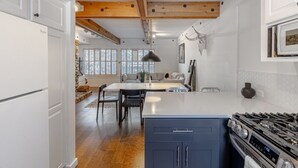 A kitchen with a central island, wooden beams, a stove, and a dining area with chairs and a table. - Stylish Sun Valley Condo w/ Resort Access! (Sun Valley)