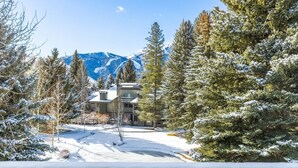 A snow-covered landscape with a building surrounded by evergreen trees and mountains in the background. - Stylish Sun Valley Condo w/ Resort Access! (Sun Valley)