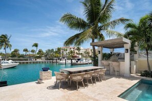 A poolside area with a table and chairs, a small pool, and a view of a marina with boats.