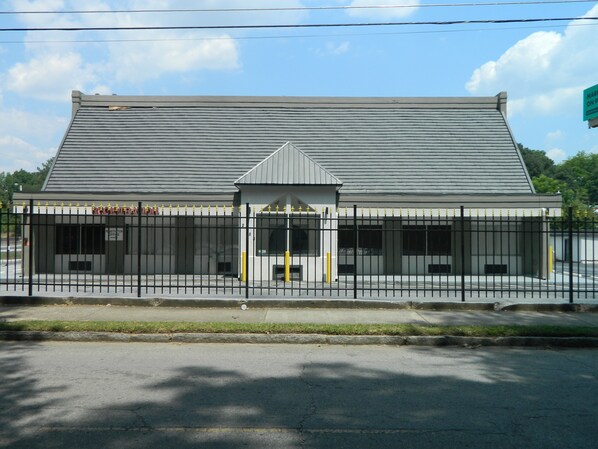 A building with a metal fence, a registration office, and a small entrance with a triangular roof. - Travel Inn Atlanta (Atlanta)
