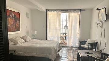 Une chambre à coucher avec un lit, un bureau, une chaise, une lampe et un tableau au mur.