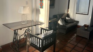 A living room with a dining table, a sofa, a chair, and a window with curtains.
