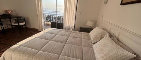 Une chambre à coucher avec un lit, une chaise, une table de chevet et une vue sur l’extérieur.