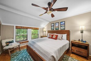 A bedroom with a bed, a ceiling fan, a nightstand, a lamp, and a window with blinds. - Four Bear Falls (Banner Elk)