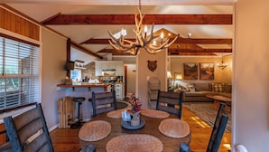 A dining area with a round wooden table, woven placemats, and a chandelier. - Four Bear Falls (Banner Elk)