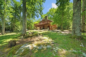 A rustic cabin surrounded by a forest with a clear sky. - Four Bear Falls (Banner Elk)