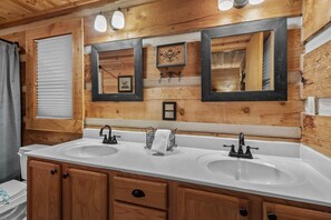 Une salle de bain avec des lambris en bois, deux lavabos et trois miroirs.