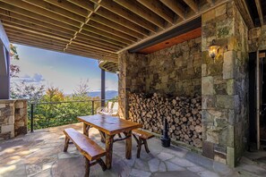 Une terrasse extérieure avec un mur en pierre, une table en bois et des bancs.