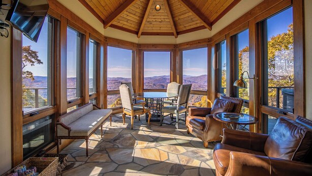 A cozy room with a stone floor, wooden ceiling, and large windows offering a mountain view. - Heavenly Daze at Eagles Nest (Banner Elk)