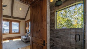 A spacious room with a large window, a wooden door, and a stone shower area. - Heavenly Daze at Eagles Nest (Banner Elk)