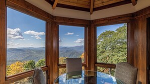 A room with a glass table and four chairs, large windows offering a mountain view. - Heavenly Daze at Eagles Nest (Banner Elk)