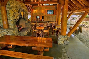Un intérieur rustique en bois, avec des murs en pierre, une cheminée en pierre, des tables et des bancs en bois, ainsi qu’un coin bar.