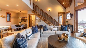 A spacious living area with a large sectional sofa, a round coffee table, and a wooden staircase. - Price Peak at Eagles Nest (Banner Elk)