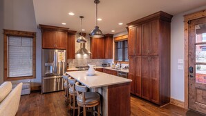 A modern kitchen with wooden cabinets, stainless steel appliances, and a central island with bar stools. - Price Peak at Eagles Nest (Banner Elk)