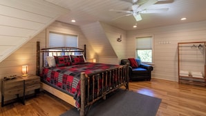 Ein Schlafzimmer mit einem hölzernen Bett, einem Deckenventilator, einem Schreibtisch und einem Fenster mit Jalousien.