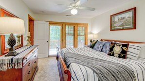 A bedroom with a bed, a dresser, a ceiling fan, and a door with a view to the outside. - Peace at Echota (Boone)