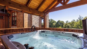 A hot tub in a wooden cabin with stone walls and a clear view of trees. - Birds Nest Retreat at Eagles Nest (Banner Elk)