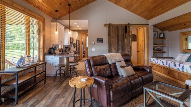 A spacious living area with a brown leather sofa, a wooden dining table, and a kitchen in the background. - Valley View (Banner Elk)