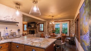 Eine Küche mit Granit-Arbeitsplatten, Holzschränken und einem Essbereich mit Steinwand und großen Fenstern.