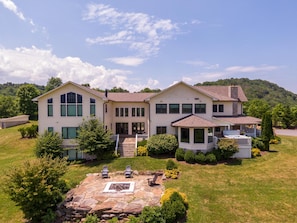 A large, two-story house with a stone patio and outdoor seating. - Sunnyside Farm (Boone)