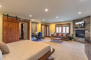 A spacious living room with a large bed, a sofa, a desk, and a fireplace. - Sunnyside Farm (Boone)