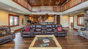 A spacious living room with a high ceiling, a fireplace, and a staircase leading to an upper level. - Sunnyside Farm (Boone)