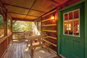 A wooden porch with benches, a green door, and a window with multiple panes. - The Apple Cabin (Blowing Rock)