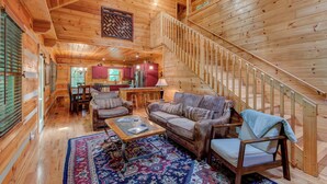 L’intérieur d’une cabane en bois comprend un coin repas, une cuisine et un escalier.