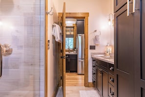 A narrow hallway leading to a kitchen with wooden flooring, a stainless steel refrigerator, and a wooden door. - Hawks Ridge at Eagles Nest (Banner Elk)