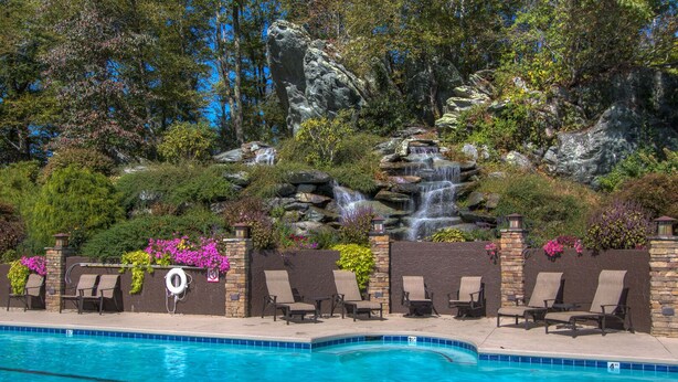 A pool with lounge chairs and a waterfall feature. - Still Lake Haven at Echota (Boone)