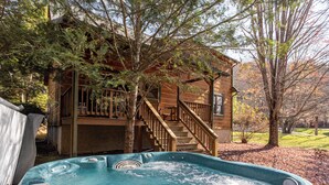 A hot tub in a backyard with a wooden deck and stairs leading to a cabin. - Baird's Creek Cabin (Vilas)