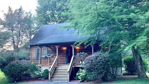 A wooden cabin with a porch, stairs, and a small garden area. - Baird's Creek Cabin (Vilas)