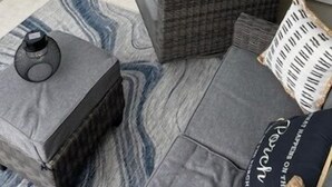 A covered patio area with a seating arrangement consisting of two gray sofas and a small table. - Crow Creek 1706 | Course-Ready, Comfort (Calabash)