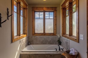 A bathroom with a large bathtub, wooden-framed windows, and a marble backsplash. - Red White & Views at Eagles Nest (Elk Park)