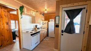 A compact kitchen with wooden cabinets, a stove, a refrigerator, and a microwave. - 2BR 1BA Cabin #2 Riverside Point Resort (Park Rapids)
