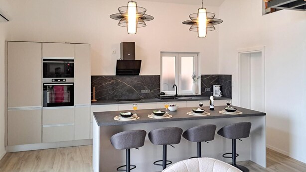 A modern kitchen with a central island, bar stools, and pendant lighting. - Gorgeous apartment in Pirovac with WiFi (Pirovac)