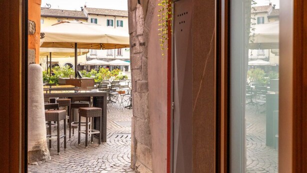An outdoor patio area with stone flooring, outdoor seating, and a view of buildings in the background.