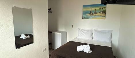 Una habitación de hotel con cama, espejo, cuadro, calentador y televisión.