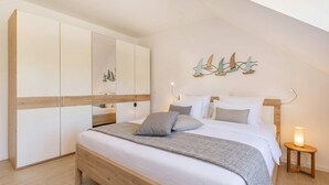 Un dormitorio con cama, armario, mesita de noche y decoración en la pared.