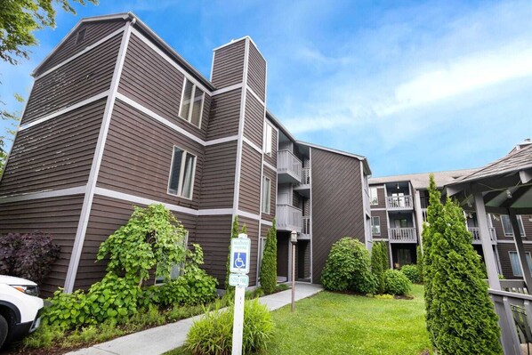 A multi-story residential building with a modern design, featuring balconies and a well-maintained garden area.