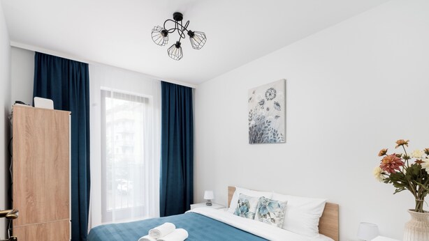 Una camera da letto moderna con un letto, un comodino, un armadio e una finestra con tende.
