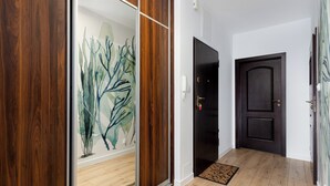 Un corridoio con pavimento in legno, una porta nera e un muro decorato con un murale di piante.