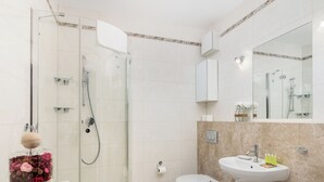 Un bagno moderno con doccia vetrata, un water, un lavandino e un cestino.