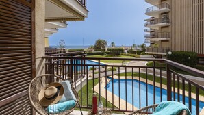 Uma varanda com vista para uma piscina, um chapéu e uma garrafa sobre uma cadeira.