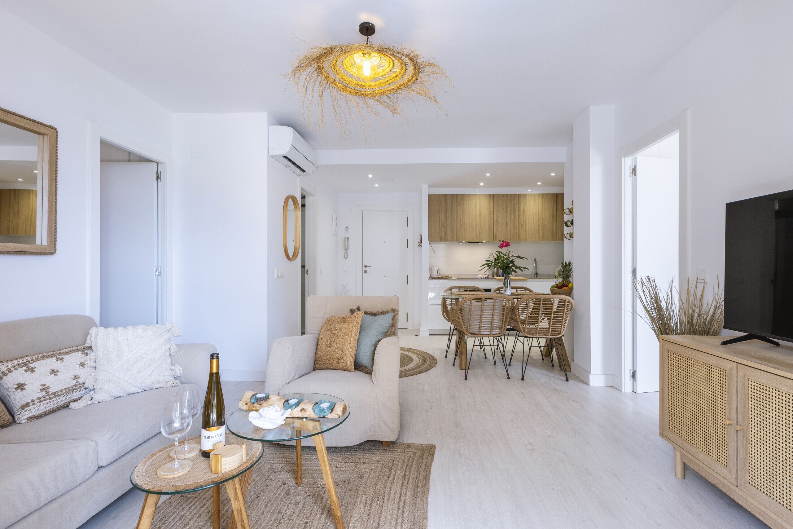 A modern living room with a sofa, coffee table, and a dining area with chairs and a table.